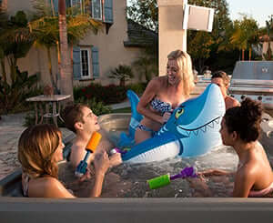 Woman on shark floaty inside of hot tubs with friends around her