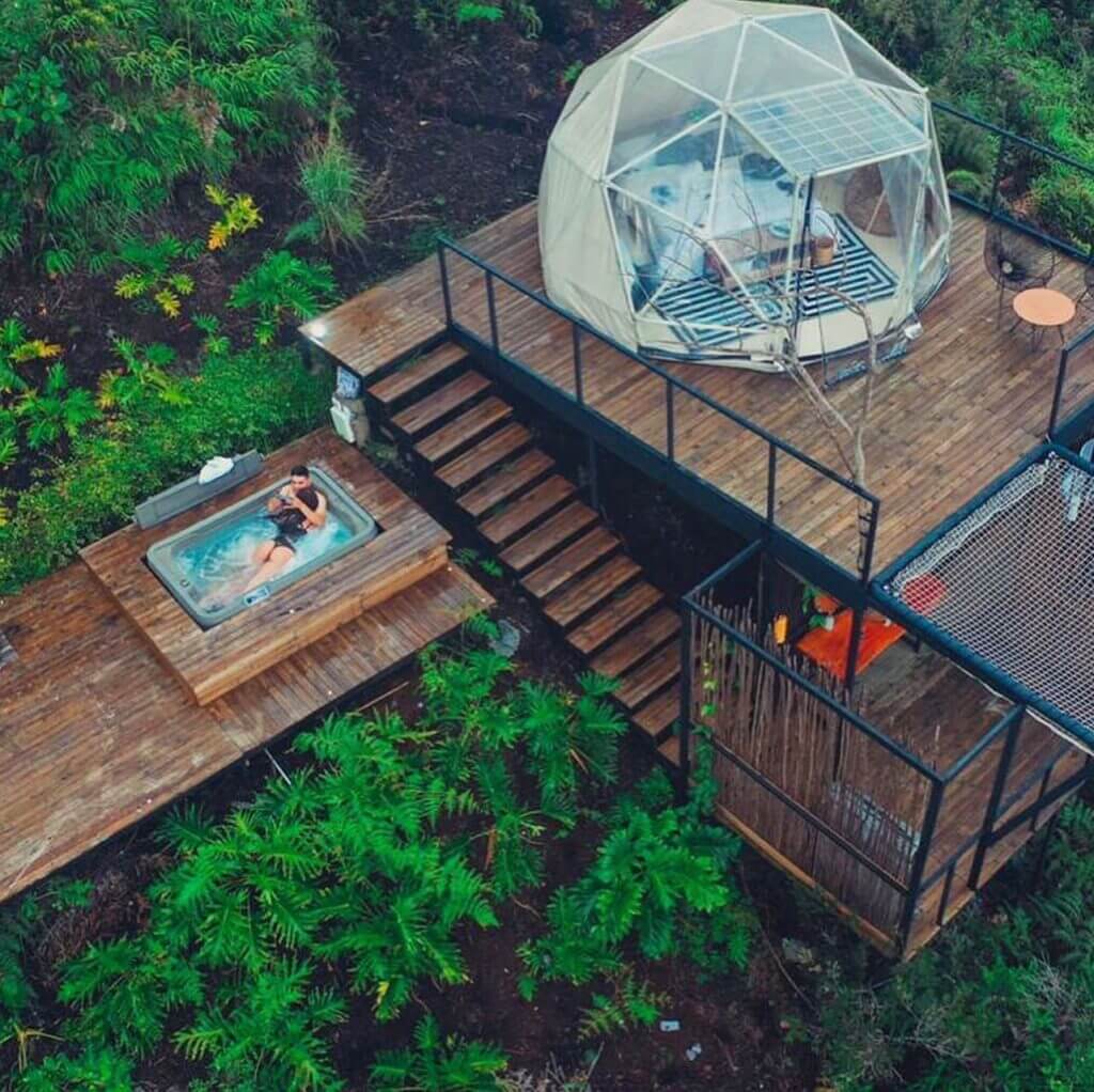 Igloo house on platform in the forest with stairs and hot tub