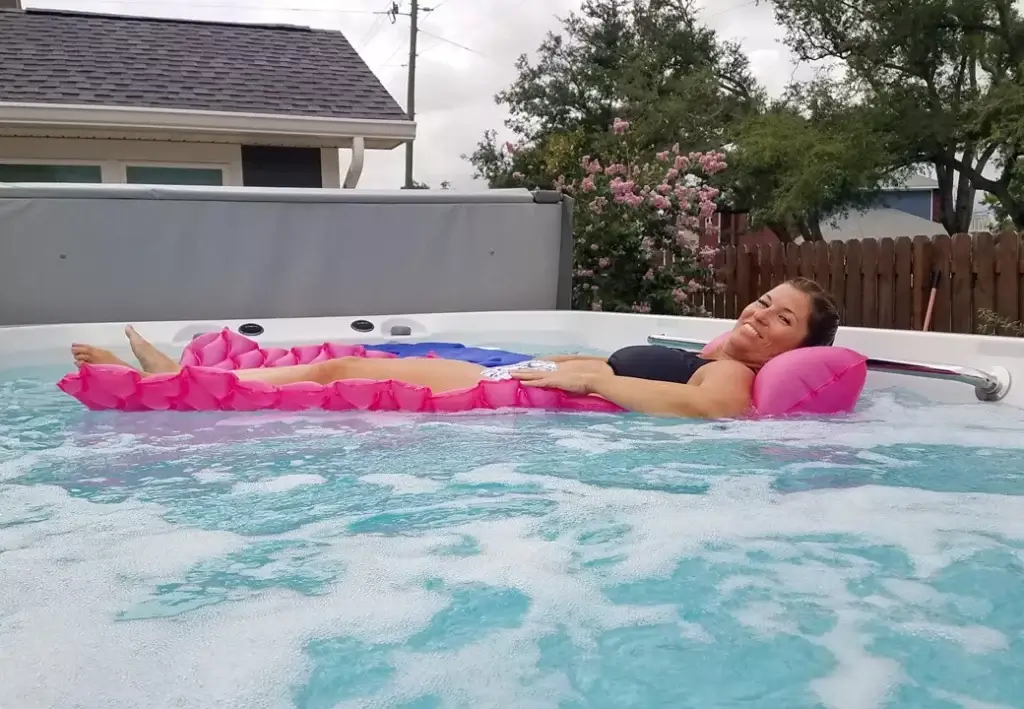 Woman on pool floaty relaxing in swim spa