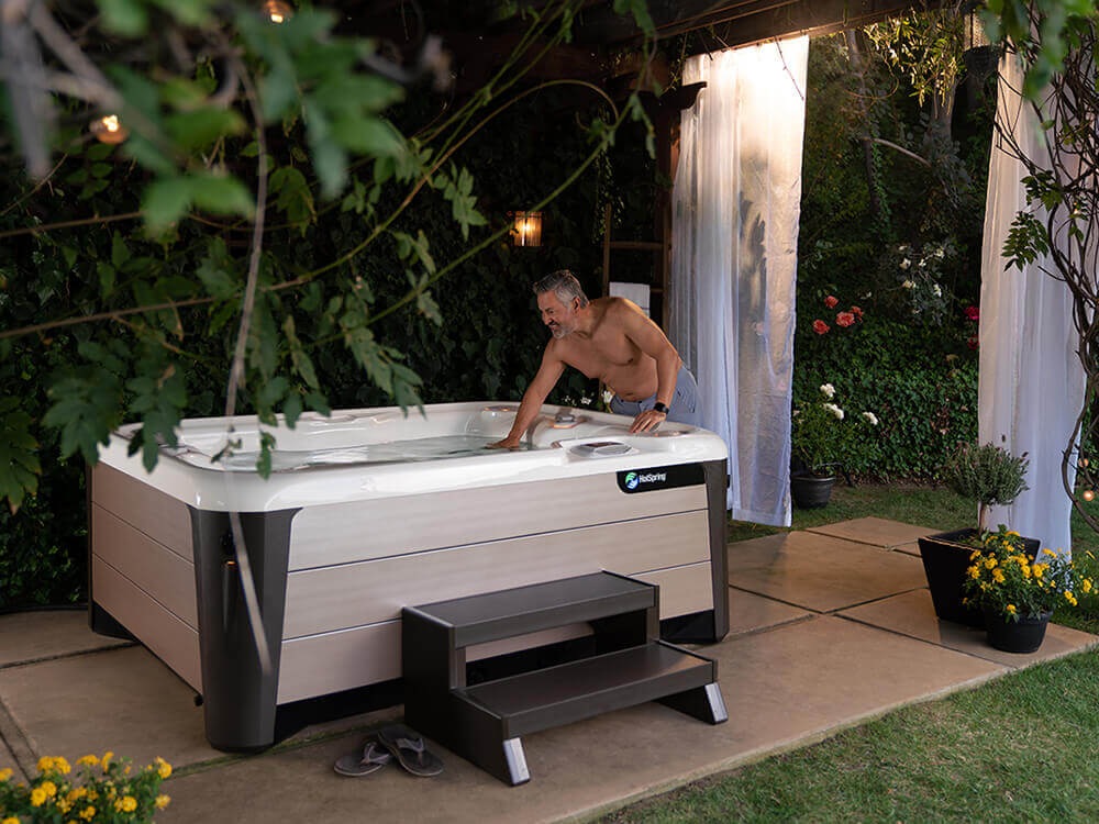 Man dipping his hand into hot tub in an outdoor oasis