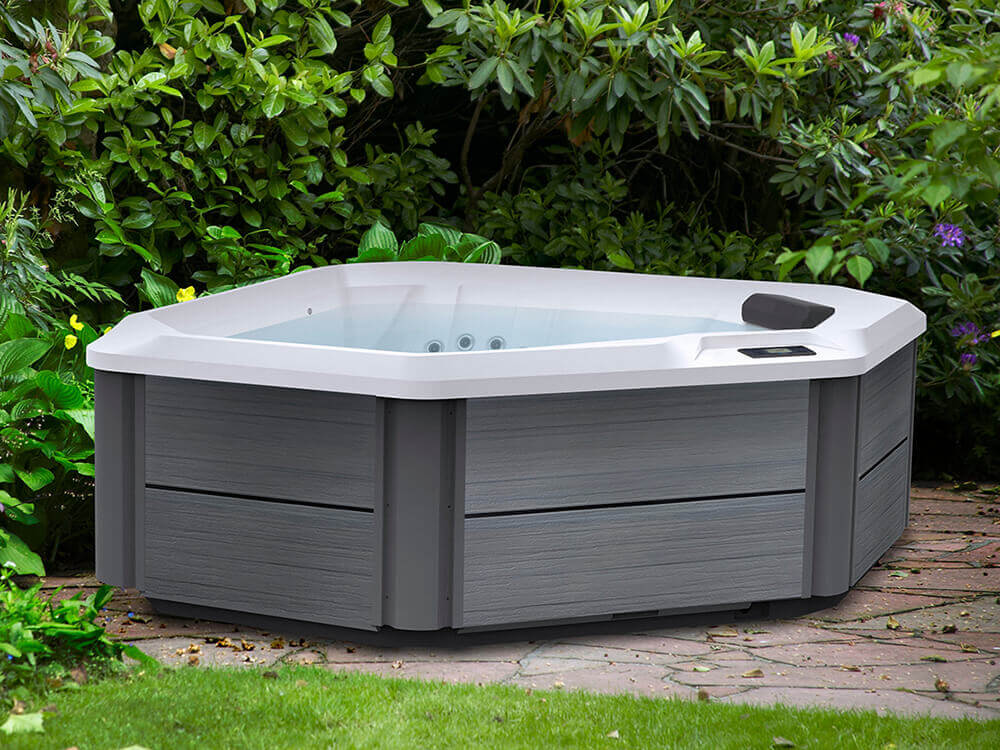 Triangular corner hot tub with gray panels on wooded patio