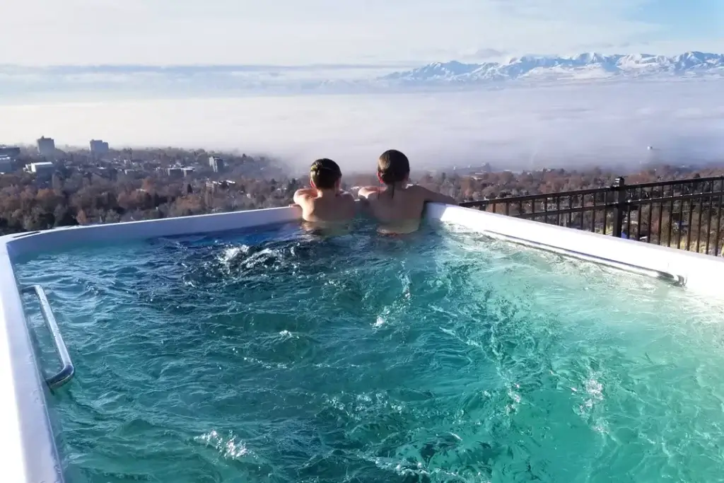 Two kids sitting in a swim spa overlooking the city