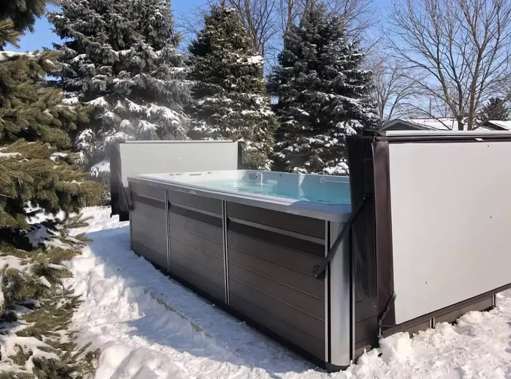 Swim Spa opened up with evergreen trees and snow surrounding it